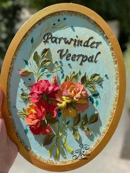 A budget-friendly oval nameboard for "Parwinder & Veerpal," featuring a lovely bouquet of sculpted roses on a soft blue background. A perfect anniversary gift.