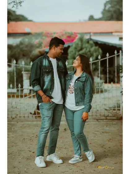 A couple in matching denim jackets looks at each other with affection. A classic, cool, and casual pre-wedding portrait.