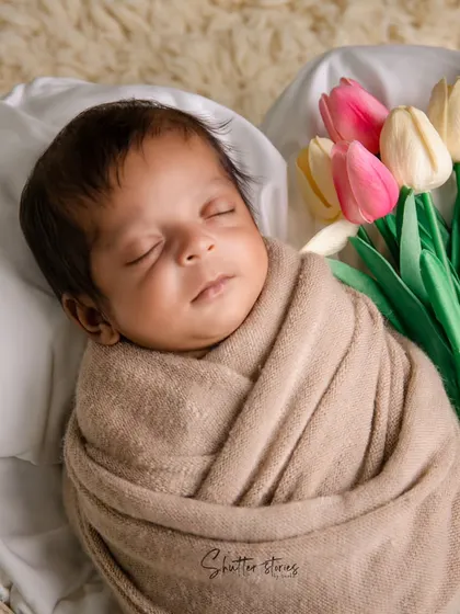 A classic and clean setup with a neutrally wrapped baby and a bouquet of tulips, adding a fresh, gentle touch of color.