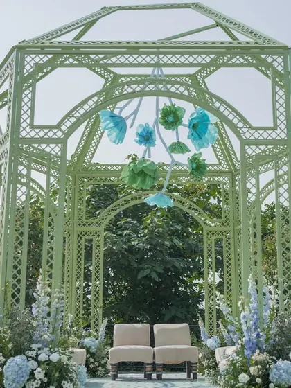 A closer look at the mint green mandap, adorned with a hanging installation of handcrafted paper flowers in shades of blue and green.