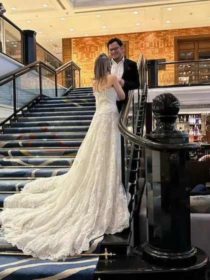 A classic fairytale moment. Our white lace wedding gown with a long train pairs perfectly with a timeless black tuxedo.