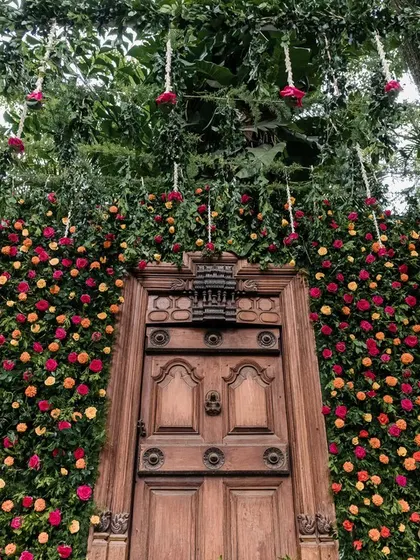 This stunning floral wall, featuring a traditional wooden door, served as a breathtaking backdrop for a wedding ceremony, blending tradition with natural beauty.