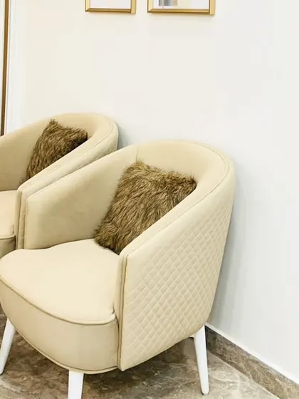 A cozy seating corner with two quilted beige armchairs. This little nook provides a perfect spot for morning coffee or a quiet conversation.