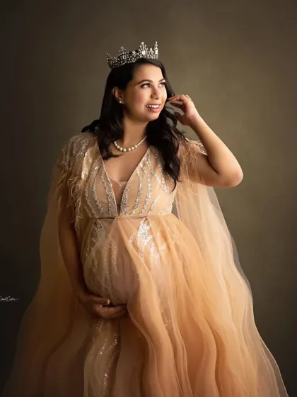 A regal portrait of a mom-to-be in a shimmering champagne-colored gown, complete with a beautiful crown.