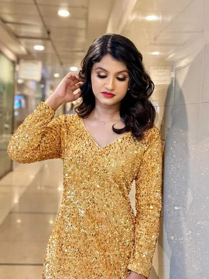 A full-length view of the model in her sparkling gold dress. The makeup complements the outfit perfectly, creating a cohesive and head-turning look that is all about glamour and confidence.