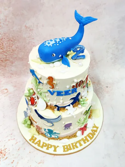 We dive deep into an underwater adventure with this two-tiered sea creatures cake. A magnificent blue whale tops the cake, which is covered in a variety of ocean friends like dolphins, stingrays, and octopuses, creating a vibrant aquatic world.
