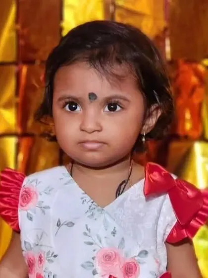 A cute toddler in a red and white floral dress with ruffled satin sleeves, looking ready for a party.
