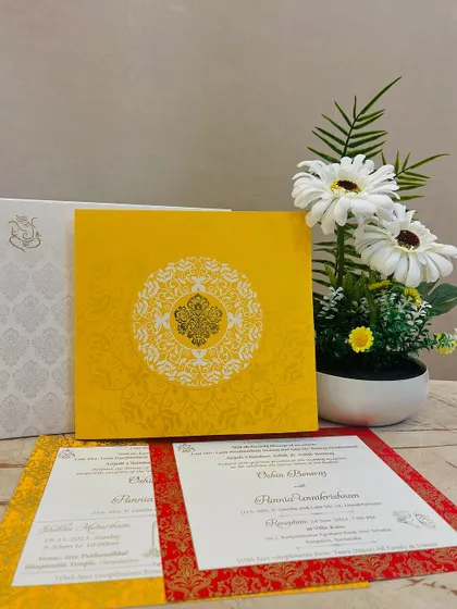 A bright and cheerful invitation set in yellow and red. The design features a traditional mandala pattern and includes inserts with classic Indian brocade borders.