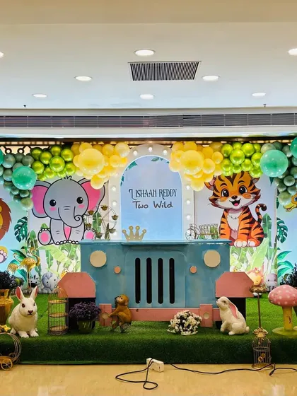 A cute cartoon jungle animal theme for a "Two Wild" birthday party, with a custom jeep-shaped table and friendly character cutouts.