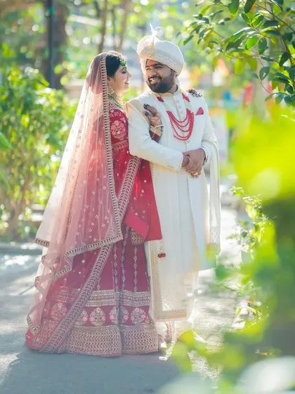 A full-length portrait of a Sindhi couple, with the bride's beautiful veil creating a soft, romantic frame around them.