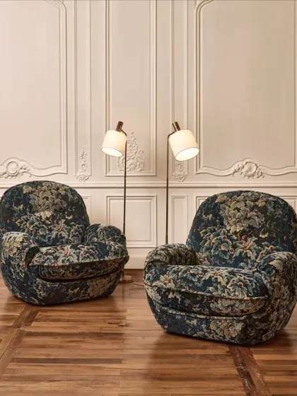 The 'Cluny' tapestry fabric by Nobilis, used to upholster these plush armchairs. The timeworn elegance of the chenille velvet and the 17th-century Verdure motif evoke a sense of history and opulent comfort.