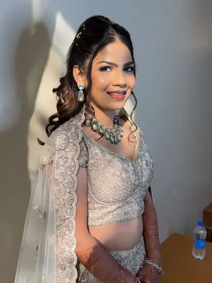 A close-up portrait showing the soft, blended makeup and the stunning silver necklace that completes her sangeet look.
