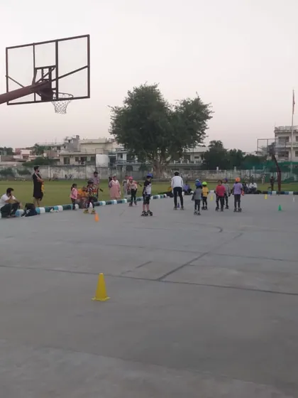 A wide view of a kids' skating session in progress on the multi-sport court. You can see parents watching from the sidelines as the children learn.