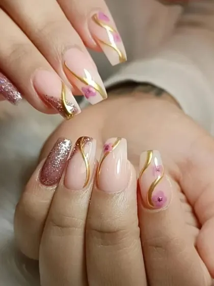 An elegant design with a nude base, rose gold glitter accents, and delicate gold swirls with tiny painted flowers.