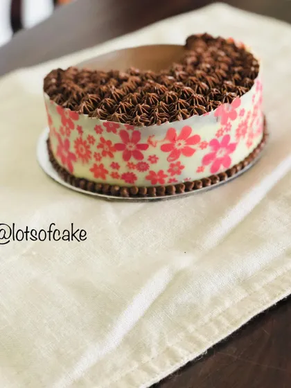 A side view of my chocolate ganache cake, showing the pretty pink floral transfer sheet on the chocolate collar and the detailed piping on top.