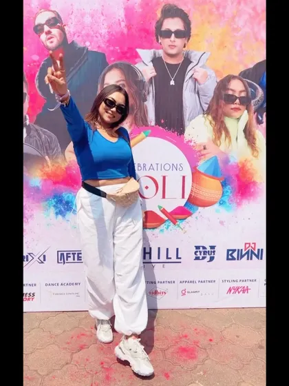 Posing in front of the event banner at a Holi celebration. Ready to bring the beats and colors to the party.
