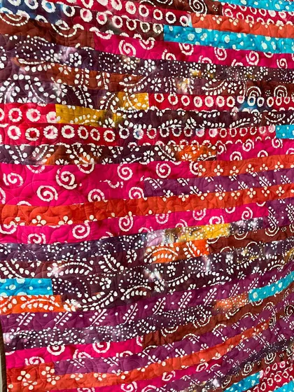 A close-up of a jelly roll quilt made with batik fabrics, showing the texture added by the longarm quilting.