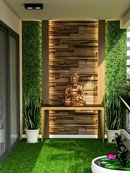 A peaceful balcony sanctuary featuring a Buddha statue as the focal point. The design uses a combination of artificial grass, a wood-paneled accent wall, and vertical gardens to create a serene space for meditation or quiet reflection.