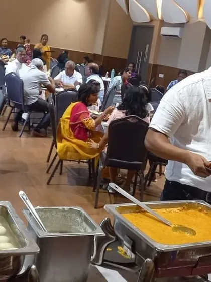 A guest helps himself to a plate of food from our extensive buffet, which includes popular Indian dishes and sweets.