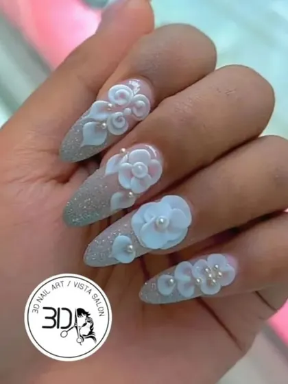 Intricate 3D floral art for a truly special occasion. These stiletto nails feature a sparkling silver glitter base, overlaid with beautifully sculpted white flowers and delicate pearl centers, creating a textured, dimensional masterpiece.