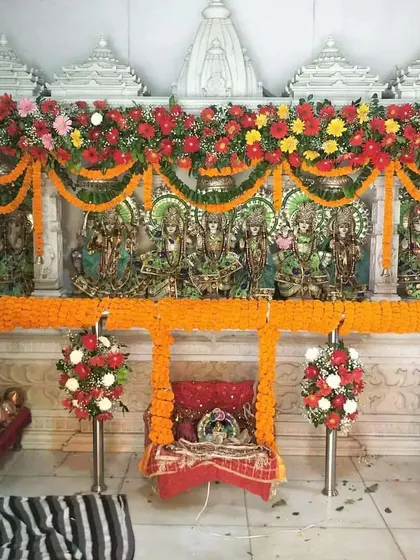 Decoration for a temple on Janmashtami. The idols are adorned with garlands of fresh marigolds and gerberas, with a small flower-decorated jhula placed in front for Bal Gopal.