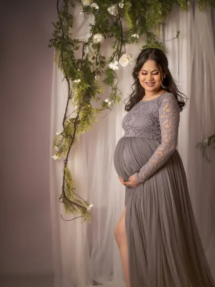 A serene portrait of the mom-to-be cradling her bump. The soft light and the delicate floral background create a peaceful and beautiful atmosphere.