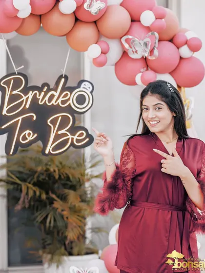 A fun shot of the bride-to-be pointing to her 'Bride to Be' sign, full of excitement and personality.