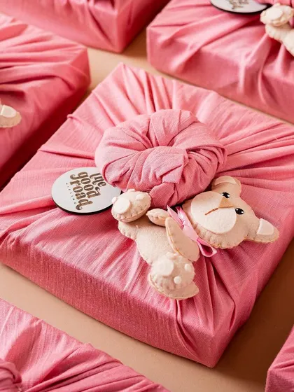 Beautifully wrapped gifts using the Furoshiki technique with a cute teddy bear detail, perfect for a baby shower or a child's birthday.