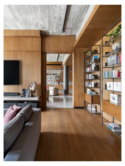 A view from the TV lounge into the main first-floor lounge of the K Residence. The use of consistent wood flooring and paneling creates a sense of architectural continuity, while the different furniture styles give each space its own distinct personality.