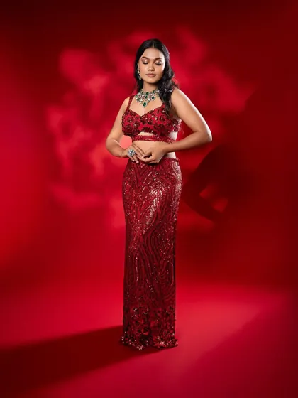 Another pose in the red gown, showing the elegant silhouette and the statement necklace.