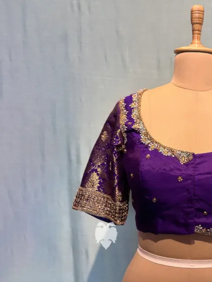 A rich purple silk blouse for Nirmala, the mother of the groom, featuring gold-silver zardosi and a highlighted sleeve border.