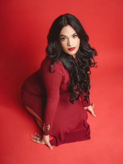 A high-angle shot from the red background series. This perspective creates a unique composition, emphasizing the model's pose and the flow of her dress.
