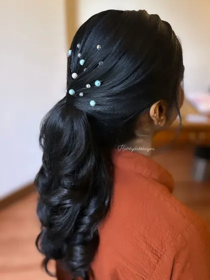 A simple, sleek ponytail with curled ends and delicate pearl and bead accessories. This shows how small details can elevate a classic style.