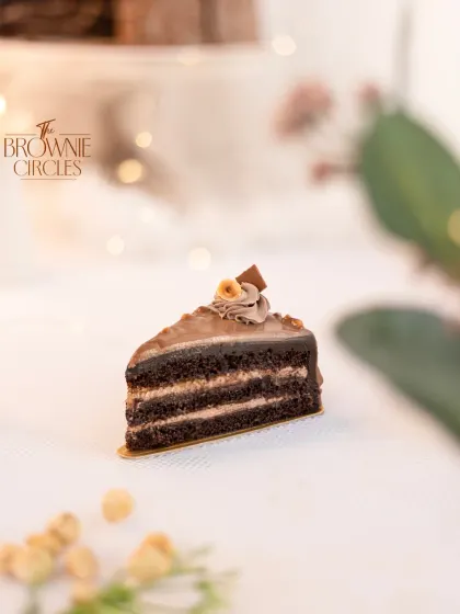 A close-up of the Coffee Hazelnut pastry slice, topped with a whole roasted hazelnut. It's a perfect pairing with a cup of coffee.