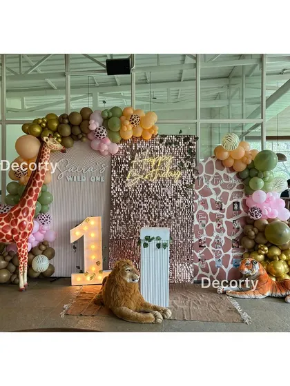 A glamorous 'Wild One' safari birthday backdrop with a sequin wall, animal props, and a light-up number one.