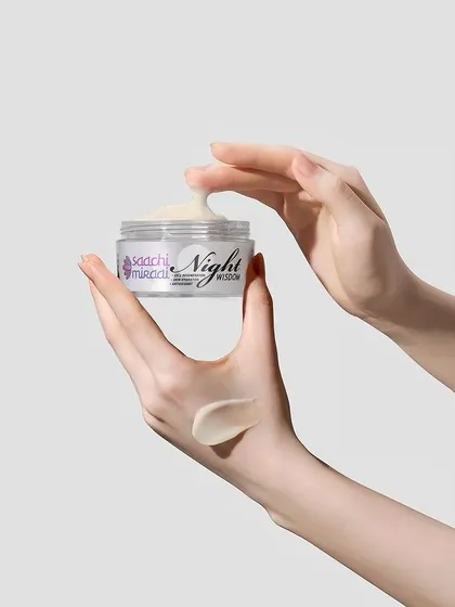 A close-up of Saachi Mirai's Night Wisdom cream, showing its rich texture being scooped from the jar. Hand-interaction shots like this make the product feel more tangible and relatable.