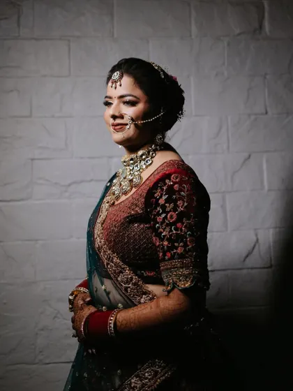 A simple and elegant portrait of the bride Payal against a white brick wall, her smile radiating warmth.