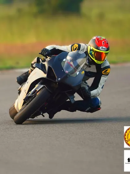 A rider demonstrating excellent form and body position, hanging off the bike to maintain stability and speed through the turn.