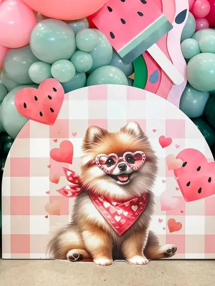 A playful "One in a Melon" theme for a first birthday party. The decor features cute watermelon graphics, heart-shaped accents, and an adorable puppy cutout, all tied together with a fresh pink and green color scheme.