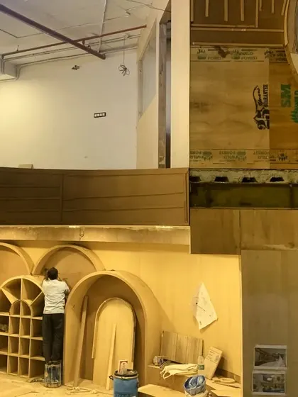 A detailed view of the arched plywood shelving and wall panels under construction.