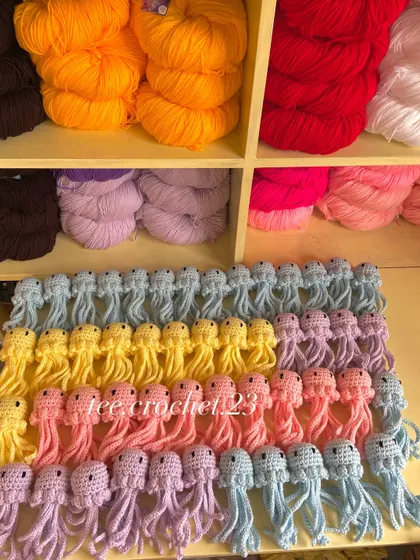 Rows of my pastel amigurumi jellyfish, available in lilac, blue, yellow, and pink for bulk orders.