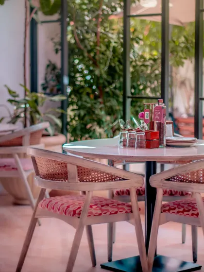 A close-up of a table setting, ready for guests. The combination of modern rattan chairs and floral upholstery adds a touch of contemporary elegance to the classic decor.