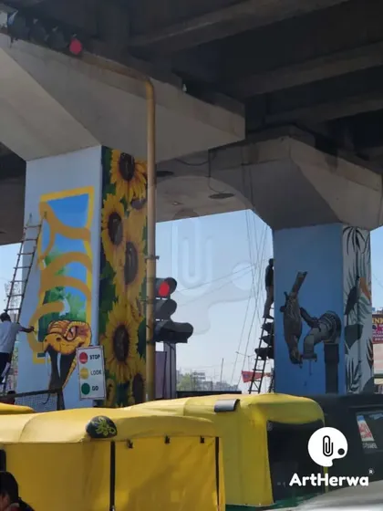This shot captures the variety of designs in the Chandigarh project, with sunflowers on one pillar and a bird on another, all being painted amidst city traffic.