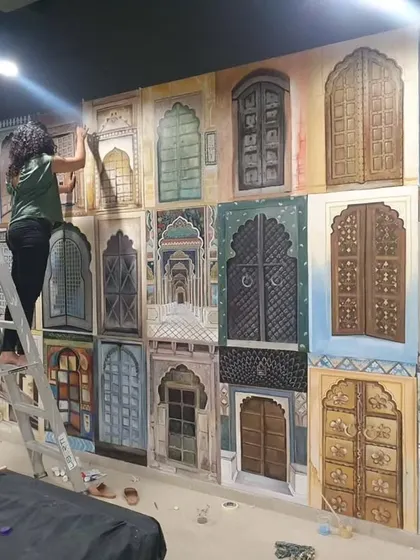 Up on the ladder, adding details to the 'Doorways of India' mural at Tablespace. Large-scale projects like this require patience, precision, and a steady hand.