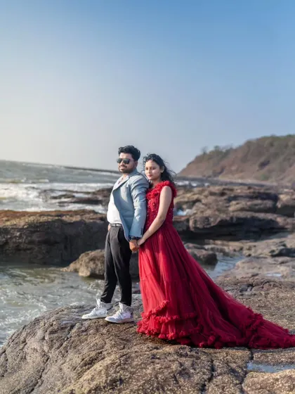 Hand in hand, standing strong by the sea. The bride's ruffled red trail gown adds texture and romance to this beautiful coastal pre-wedding photograph.