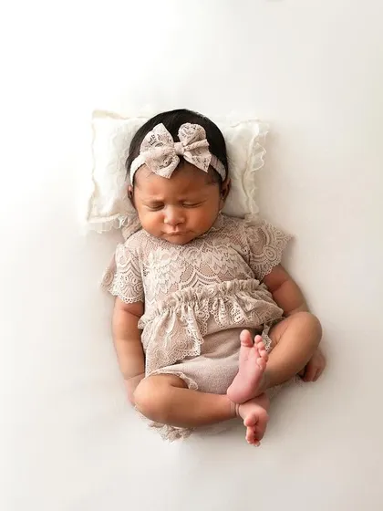 A full-body shot of the baby in her lace outfit. This pose is great for showing just how tiny and curled-up newborns are.