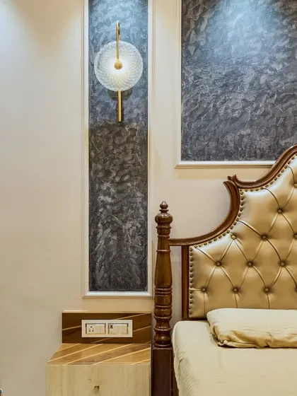 A close-up of the bedside area, showing the classic carved bedpost, the textured wall finish, and the modern wall lamp. This mix of styles creates a unique and eclectic look.