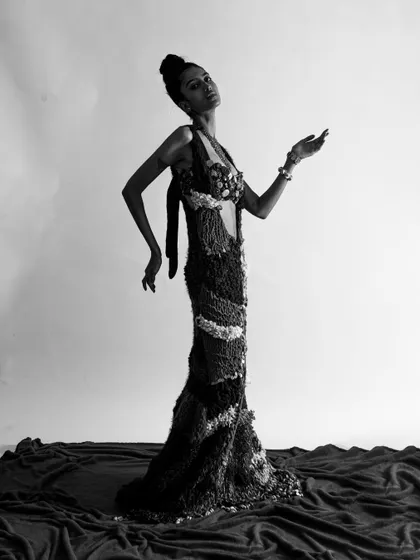A graceful black and white shot showcasing the full length of the avant-garde dress. The pose is elegant and statuesque.