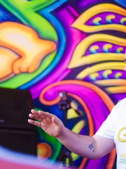 A portrait of another DJ at the decks, with the vibrant stage art creating a dynamic background.