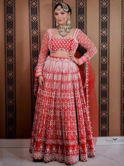 A confident pose from the bride in her red and white lehenga. This full-length portrait showcases the modern design and elegant silhouette of the bridal attire.